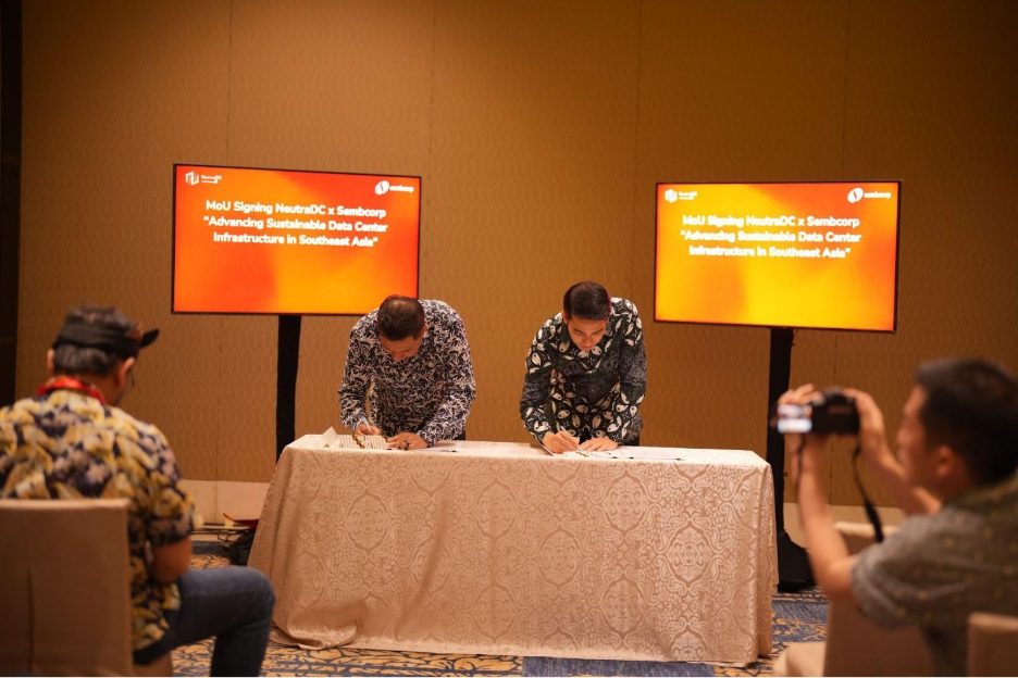 A group of people signing a document

Description automatically generated